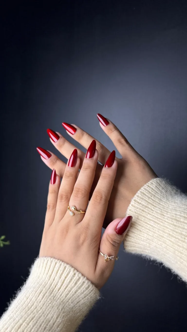 Medium length red almond press-on nails with a cream knit sleeve